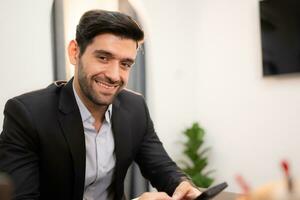 Portrait of a handsome young businessman using smartphone in office. photo