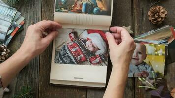 Hands place printed Christmas photos in family picture album. video