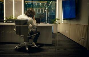 Side view of young businessman sitting at desk in office and looking away, Business disappointment concept photo