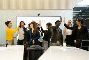 A group of multiracial businesspeople hands raise to celebrate success in front of the meeting room, indicating the concept of business success. photo