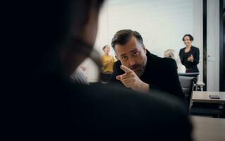 Serious mature businessman explaining something to his colleague during meeting in office photo