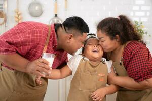 A plus-size family with a father wearing a prosthetic leg, Eat together after cooking and daughter drinks milk for health in the dining room of the house photo