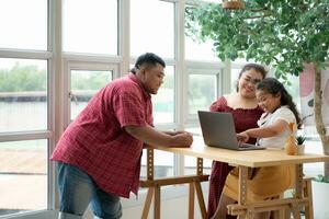 un talla extra familia con un padre vistiendo un protésico pierna, es felizmente ayudando un niño con su deberes y teniendo divertido juntos en el balcón de el casa foto