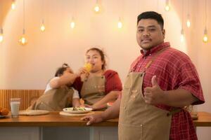 A plus-size family with a father wearing a prosthetic leg, Eat together after cooking and daughter drinks milk for health in the dining room of the house photo