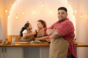 A plus-size family with a father wearing a prosthetic leg, Eat together after cooking and daughter drinks milk for health in the dining room of the house photo