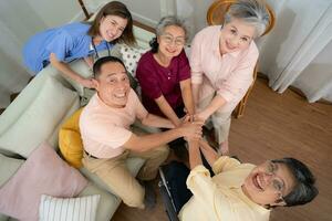 parte superior ver de asiático mayor familia participación manos juntos en vivo habitación a hogar foto