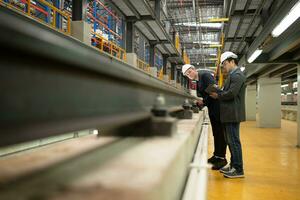 dos empresarios inspeccionar carril trabajo a reserva equipo para utilizar en reparando pistas y maquinaria de el eléctrico tren transporte sistema. foto