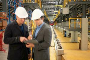 Two businessmen inspect the electric train system using a tablet to reserve equipment for use in repairing tracks and machinery of the electric train transportation system. photo