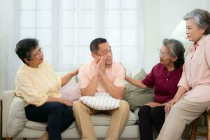 Senior Asian man suffering from serious illness sitting on the sofa With friends coming to visit and give encouragement for the treatment. photo