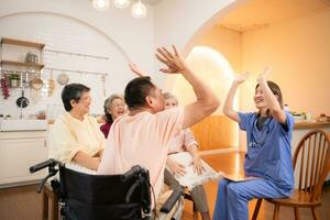 Group of elderly and senior man in wheelchair with nurse at nursing home Play a fun game of hitting each other's hands. Elderly people in nursing home concept photo