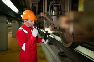 Electric train engineer use a walkie-talkie to inspect electric train machinery according to inspection round after the electric train is parked in the electric train's repair shop photo