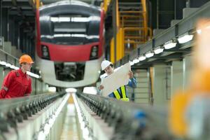 después el eléctrico tren es estacionado en el eléctrico tren reparar comercio, eléctrico tren ingeniero y técnico con herramientas inspeccionar el ferrocarril y eléctrico trenes en conformidad con el inspección redondo foto