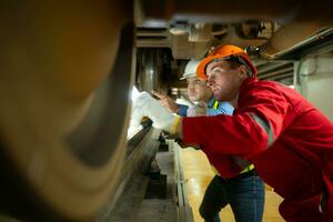 dos ingenieros para eléctrico trenes después detector dificultades con el eléctrico tren maquinaria utilizar reflectores a localizar y cheque dañado secciones. en el eléctrico tren reparar tienda foto