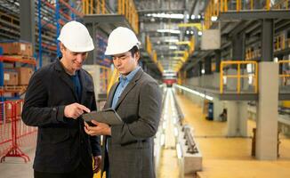 Two businessmen inspect the electric train system using a tablet to reserve equipment for use in repairing tracks and machinery of the electric train transportation system. photo