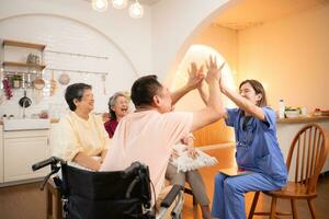 Group of elderly and senior man in wheelchair with nurse at nursing home Play a fun game of hitting each other's hands. Elderly people in nursing home concept photo