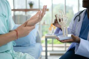 médico demostración modelo de dedo huesos a paciente en hospital. médico y cuidado de la salud concepto. foto