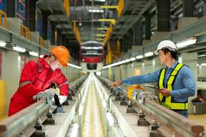 después el eléctrico tren es estacionado en el eléctrico tren reparar comercio, eléctrico tren ingeniero y técnico con herramientas inspeccionar el ferrocarril y eléctrico trenes en conformidad con el inspección redondo foto