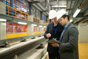 Two businessmen inspect rail work to reserve equipment for use in repairing tracks and machinery of the electric train transportation system. photo