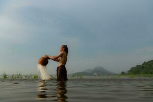 Fishermen using traditional fishing equipment After catching fish, clean up and play in the water. photo