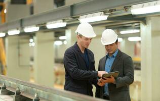 Two businessmen inspect rail work to reserve equipment for use in repairing tracks and machinery of the electric train transportation system. photo