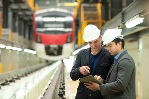 Two businessmen inspect rail work to reserve equipment for use in repairing tracks and machinery of the electric train transportation system. photo