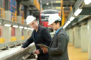 Two businessmen inspect rail work to reserve equipment for use in repairing tracks and machinery of the electric train transportation system. photo