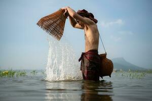 Fisherman using traditional fishing gear to catch fish for cooking, Rural Thailand living life concept photo