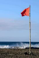 a red flag on the beach near the ocean photo