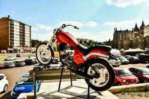 a red motorcycle is parked on a stand in front of a building photo