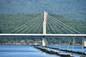 a bridge spanning over the water with mountains in the background photo