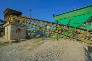 a conveyor belt and a large pile of gravel photo