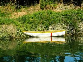a boat is sitting on the water near some grass photo