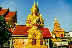 a golden statue of a buddha in front of a building photo