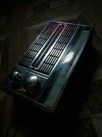 Radio receiver - box radio in black, retro technology. Radio on wooden floor. Soft focus photo