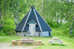 a small wooden hut with a fire pit in the middle of the woods photo