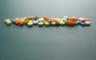 Many colorful pills arrange in row on green background photo