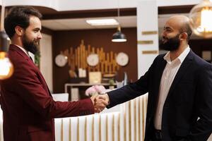 Business partners agreeing on collab, travelling for work to attend important corporate meeting. Two executive managers shaking hands in agreement to start fruitful partnership. photo