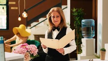 Hotel concierge reviewing bookings or reservations, working at reception in lobby to help travellers with check in procedure. Receptionist in front desk, tropical exotic resort. photo