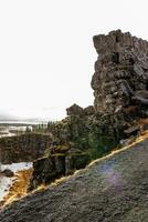natural volcánico rocoso acantilados formar montaña pared en islandés nacional parque, majestuoso tierras altas colinas hecho de hormigón Roca. hermosa Islandia desierto en nórdico thingvellir valle. foto