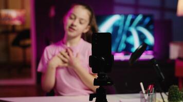 Close up shot of recording gear used by Gen z kid to film for online channel, talking with viewers. Focus on smartphone used by Kid in blurry background discussing topics with young audience video