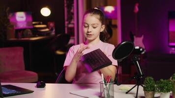 kind inhoud Schepper filmen toetsenbord recensie in huis studio, drukken verschillend toetsen naar tonen typen mogelijkheden. weinig meisje presentatie van computer randapparatuur naar publiek Aan gen z online kanaal video