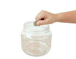 Child hand putting coin into transparent plastic money bottle or piggy bank isolated on white background with clipping path. Concept of saving money for the future or money growth photo