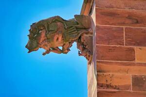 Old gargoyle from the medieval times on the side of the Freiburg Minster. Art made of red sandstone from the Middle Ages. photo