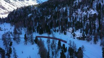 Zug im Schweiz im sonnig Winter Tag. Bernina Eisenbahn. schweizerisch Alpen. Antenne Sicht. Drohne fliegt rückwärts und nach oben video