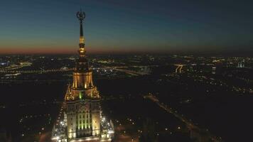 iluminado Moscú estado Universidad y paisaje urbano en Mañana crepúsculo. Rusia. aéreo vista. zumbido es volador adelante y hacia arriba y que se acerca a aguja video