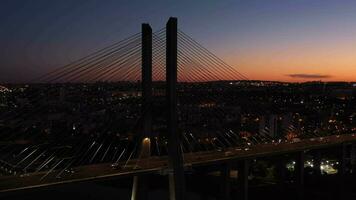 illuminato vasco da gama strallato ponte e Lisbona paesaggio urbano a sera crepuscolo. Lisbona, Portogallo. blu ora. aereo Visualizza. orbitante. medio tiro video