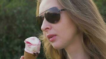 Young caucasian woman in sunglasses is licking ice cream. Close-up shot. Slow motion. video