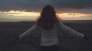 Woman is raising her hands on the top of mountain at dusk. video