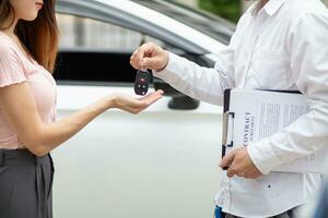 car dealer delivers keys to customer after  customer has selected car they want and agreed to buy the car with the dealer. The concept of entering into a sales contract with a trusted distributor photo