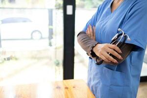 hembra médico en uniforme participación un estetoscopio esperando a examinar un paciente. un hembra médico sostiene un estetoscopio a preparar para tratando pacientes en el hospital. Copiar espacio para insertando médico texto foto